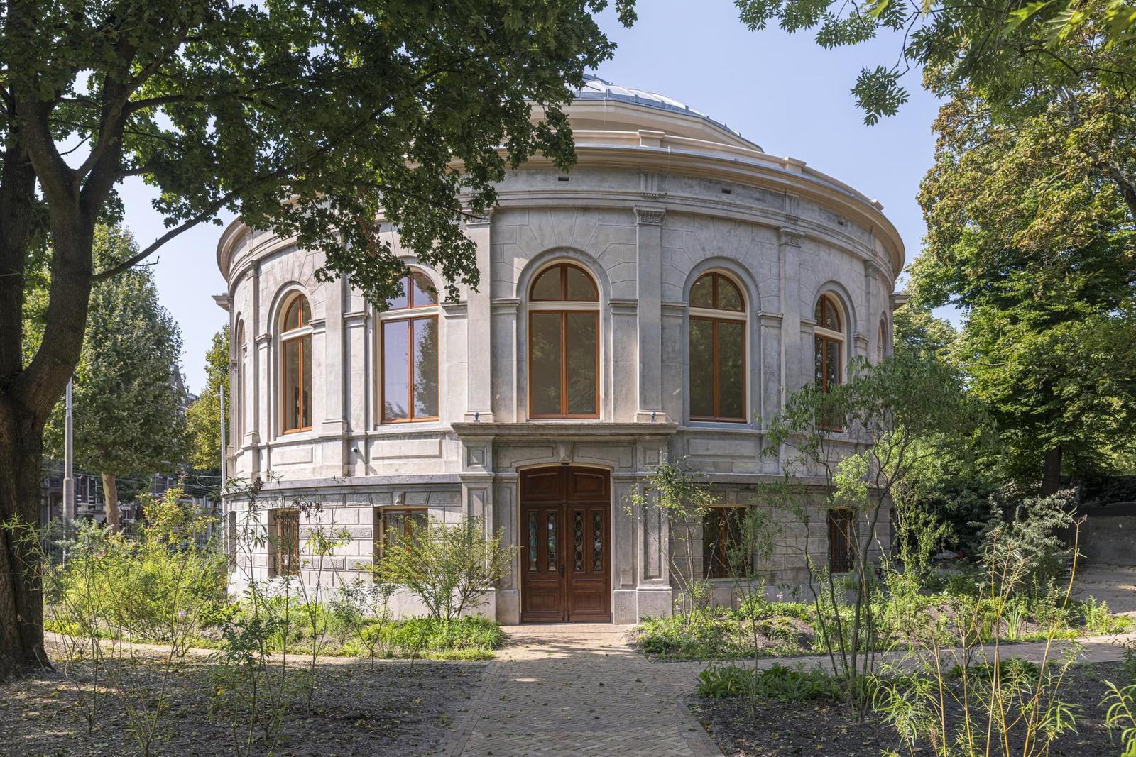 De monumentale ronde buitenkant van het ARTIS-Aquarium uit 1882, omringd door groen