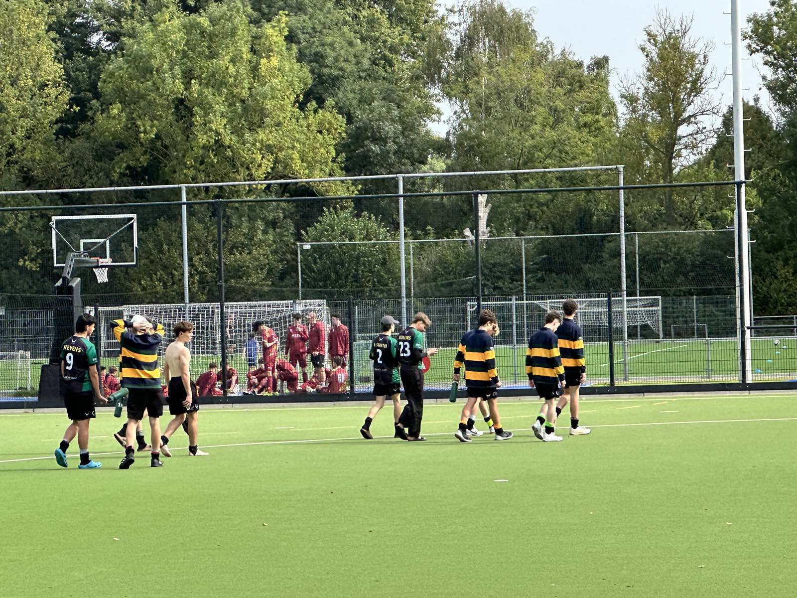 Spelers van verschillende clubs in uiteenlopende tenues lopen over het veld tussen twee wedstrijden door