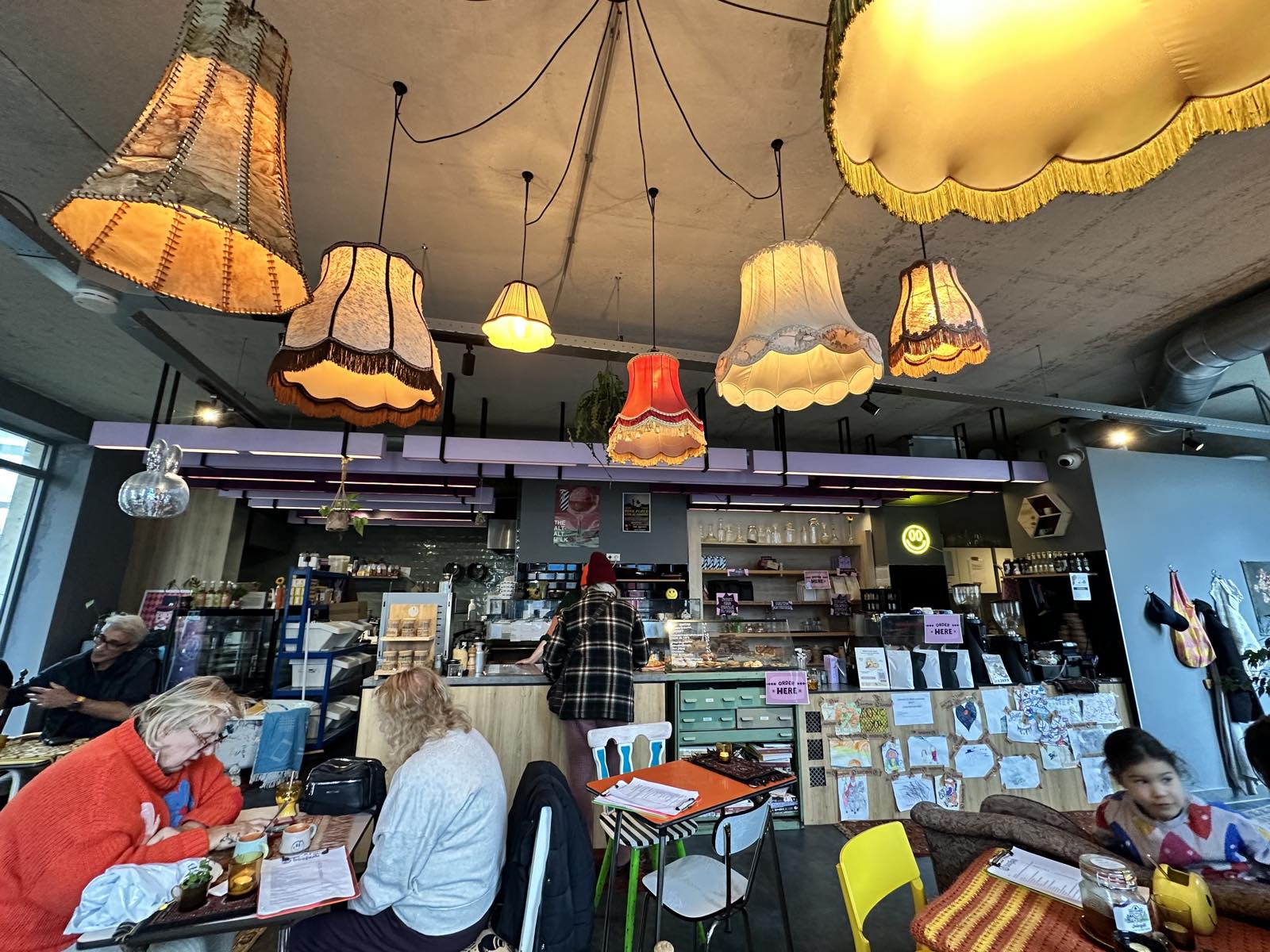 Gasten aan tafel in een buurtcafé op het eiland, onder een verzameling ouderwetse lampenkappen