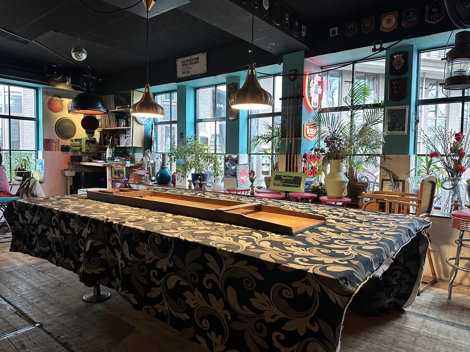 Het interieur van buurtcafé De Oceaan met een grote gedekte tafel en een sjoelbak