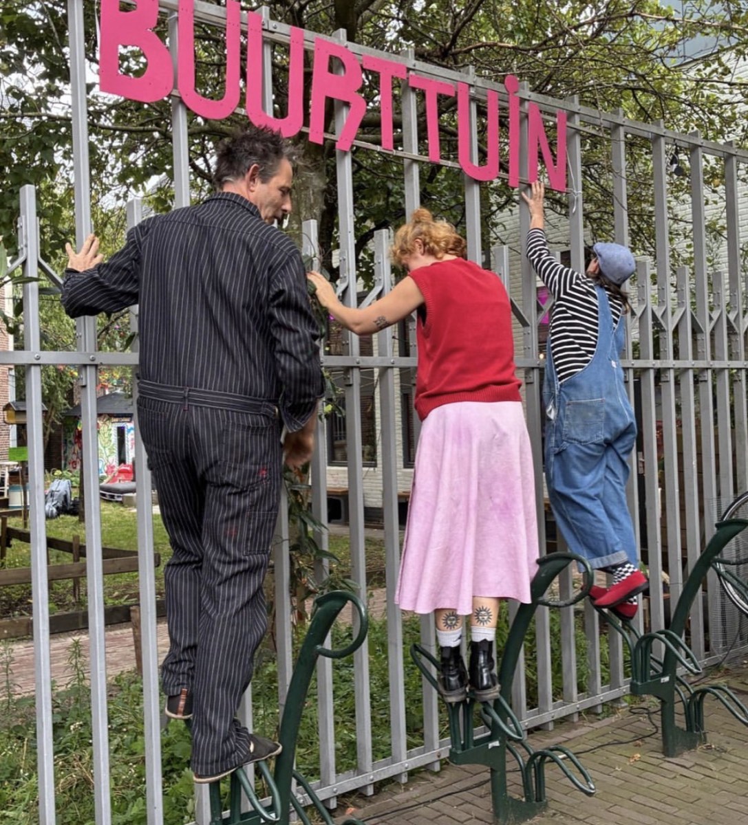 Het bord met ‘Buurttuin’ wordt opgehangen aan het hek