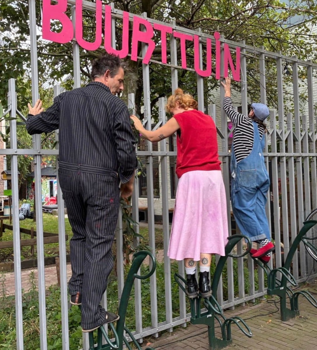 Het bord met ‘Buurttuin’ wordt opgehangen aan het hek