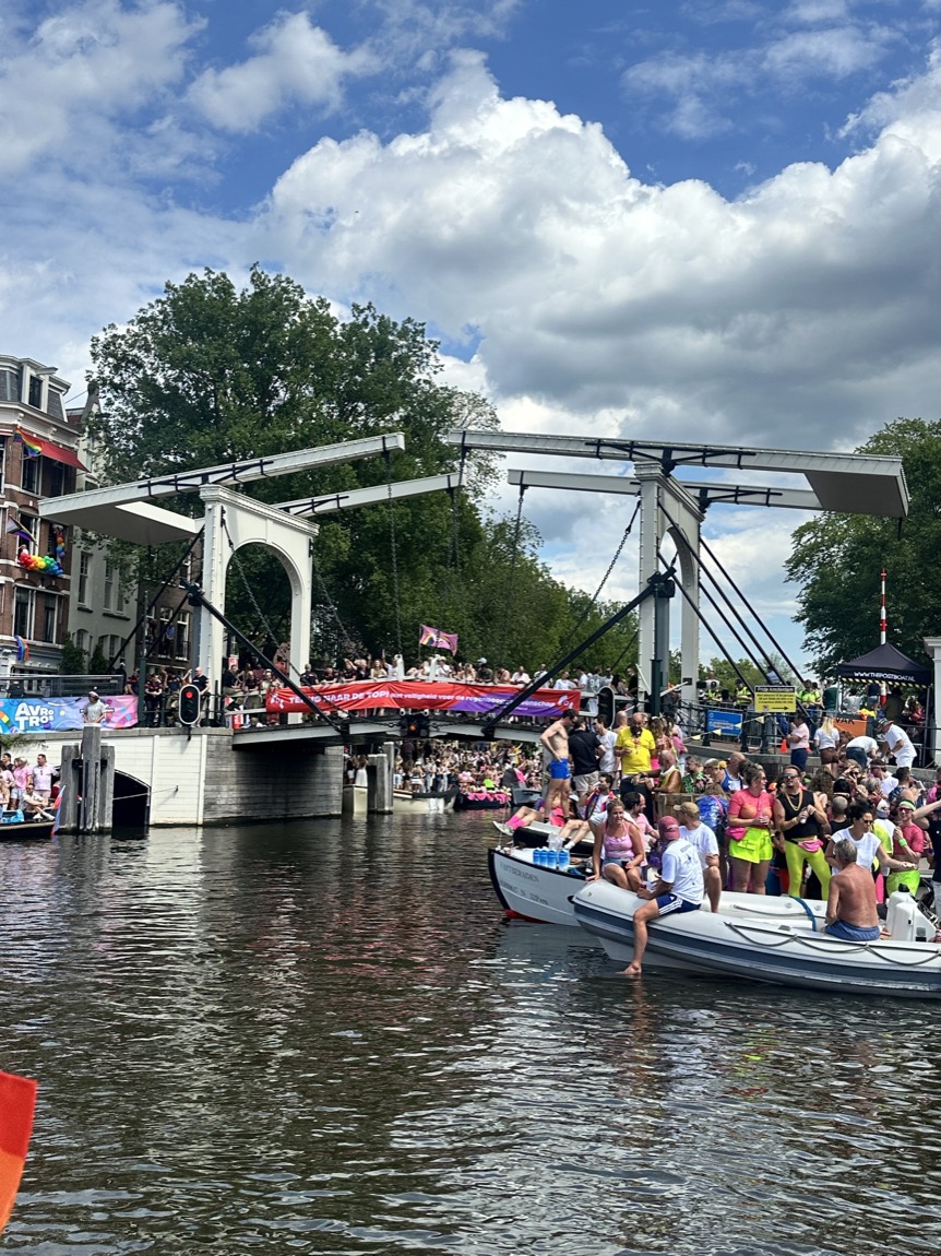 Publiek staat rijen dik op de kade langs de gracht om de Canal Parade te bekijken