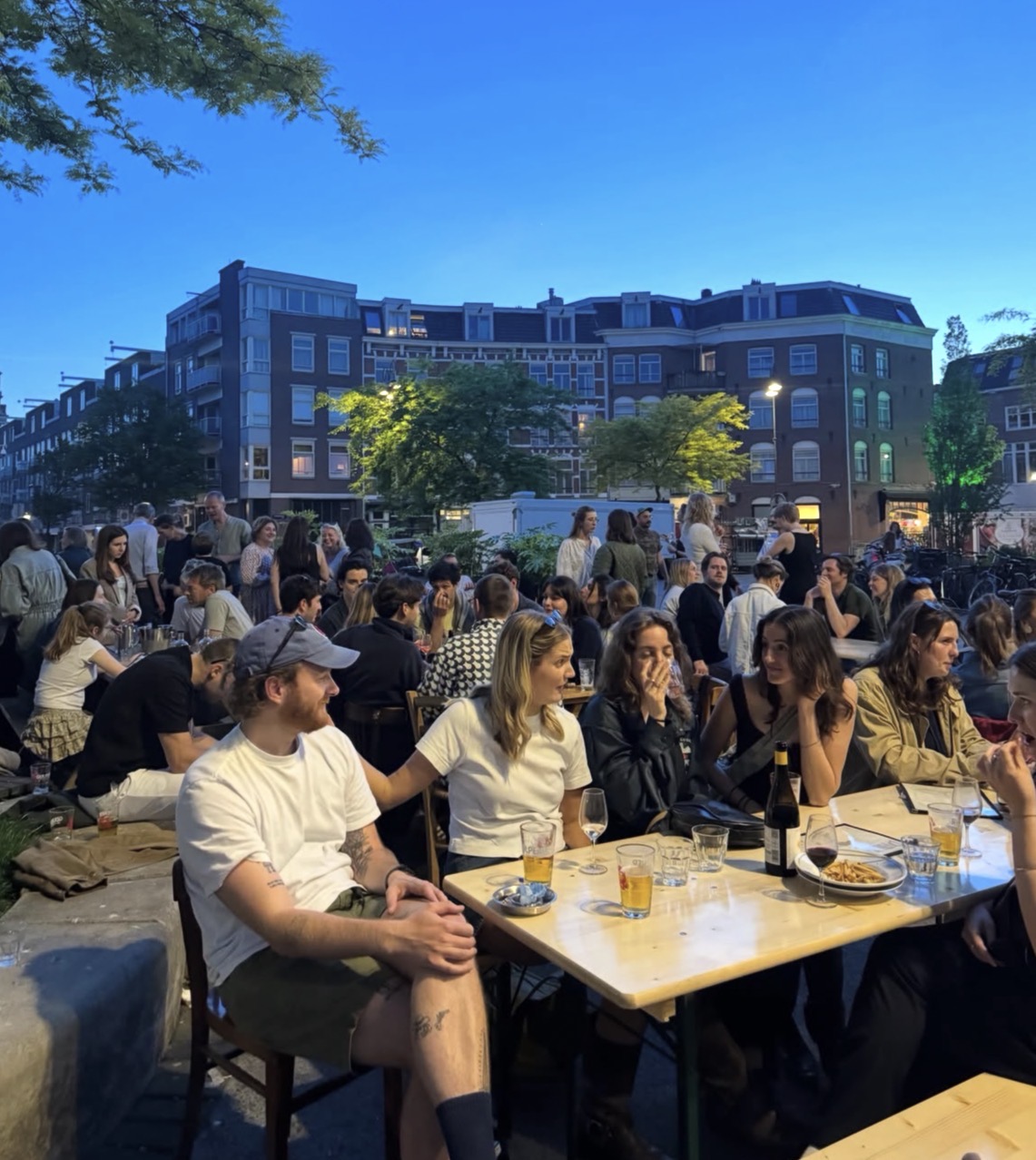 Een druk terras van Café Publiek aan het Dapperplein in de avond