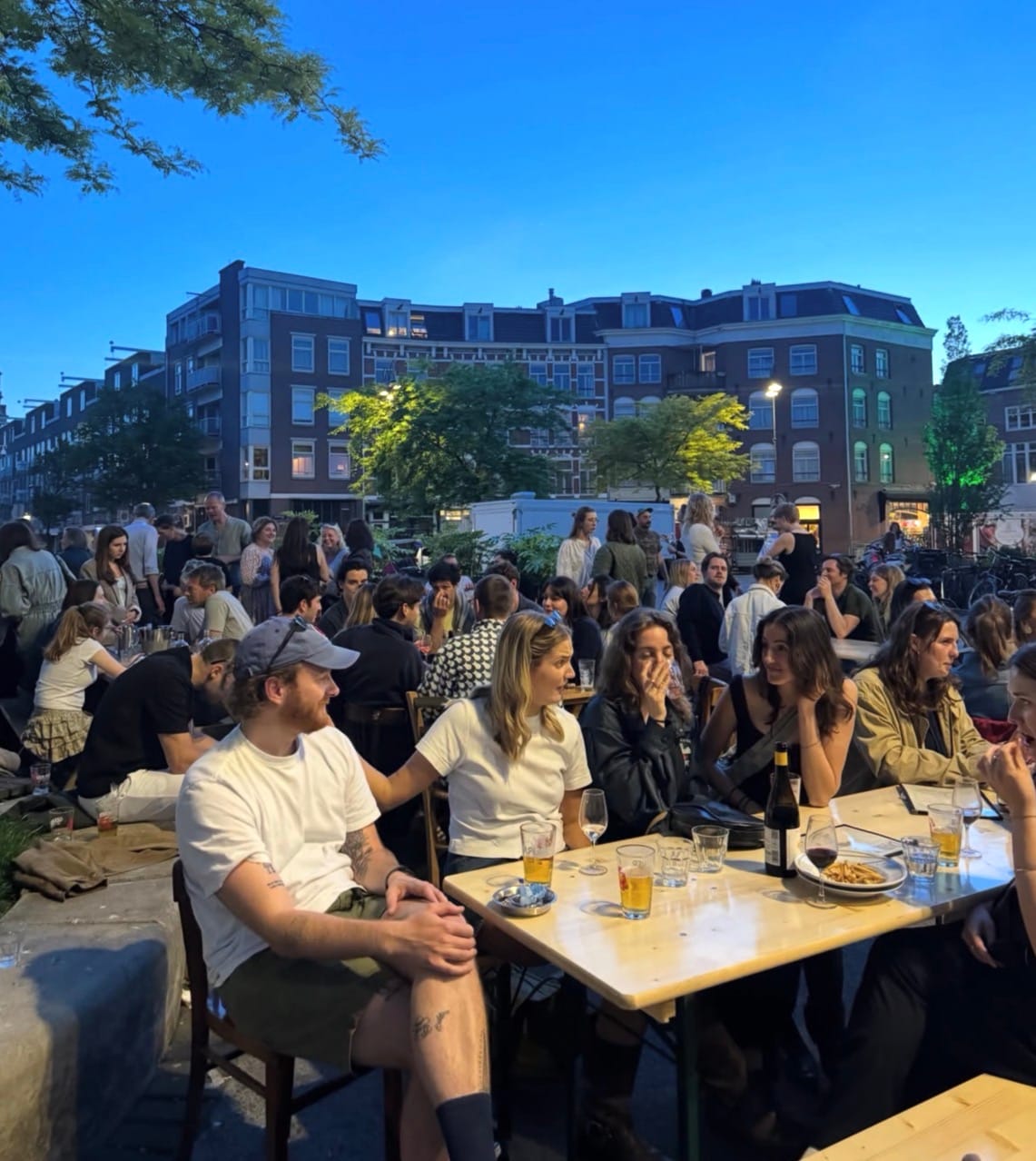 Een druk terras van Café Publiek aan het Dapperplein in de avond