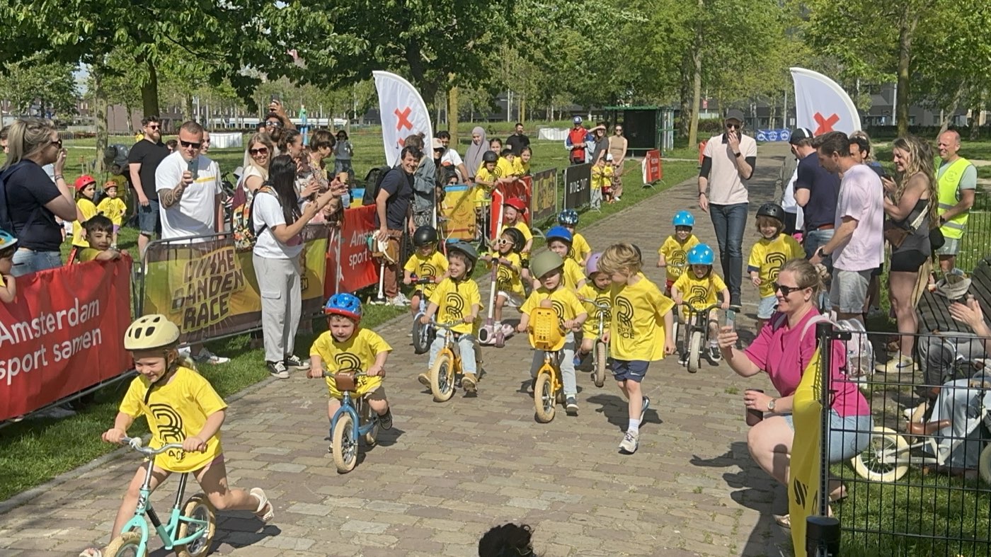 Een groep kinderen fietst en rent tijdens een eerdere Dikke Banden Race, aangemoedigd door omstanders