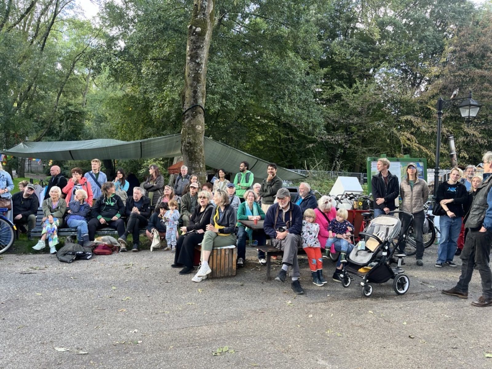 Bezoekers luisteren naar het optreden tijdens het buurtfeest in het Flevopark