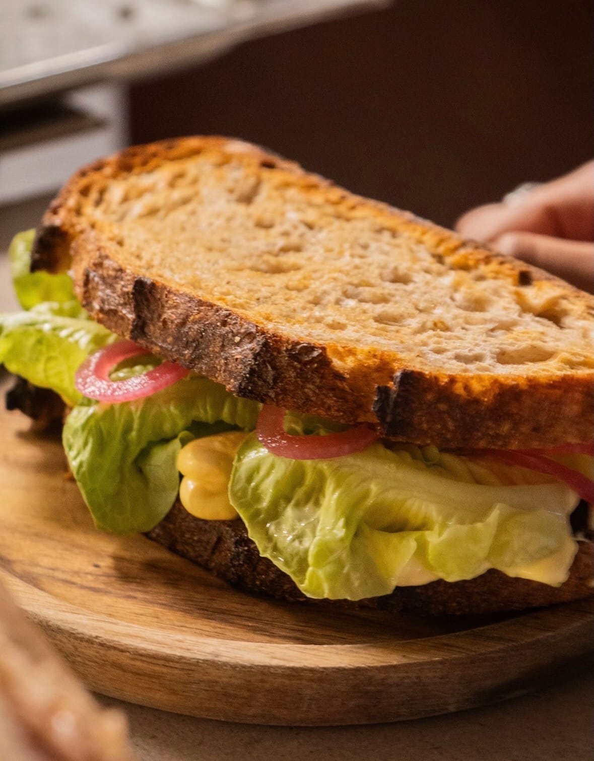Een sandwich van zuurdesembrood met sla, rode ui en saus, uit de keuken van Hearth