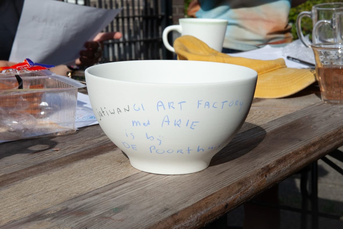 Een handbeschilderde kom met de tekst ‘Jatiwangi Art Factory met Arie is bij De Poorthuisjes’