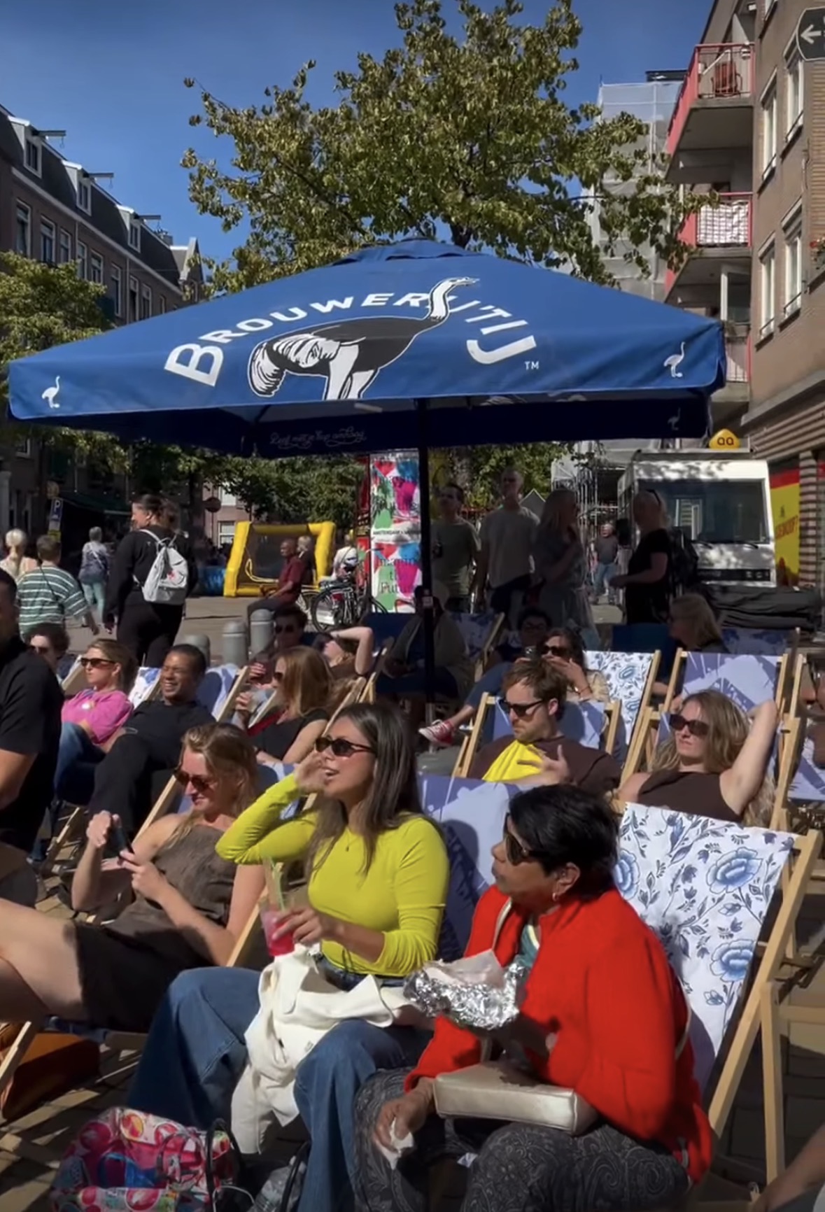 Bezoekers ontspannen in ligstoelen onder een parasol van Brouwerij ’t IJ tijdens het festival