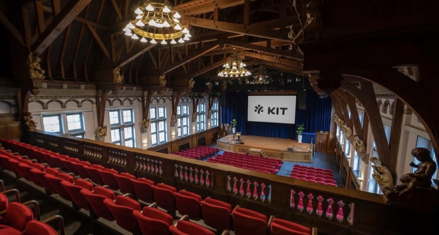 Het auditorium van KIT, met rode theaterstoelen gericht op het podium
