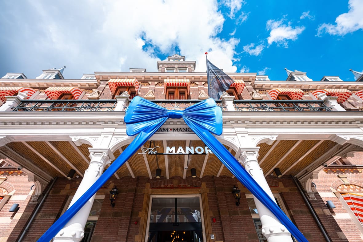 De gevel van The Manor aan de Linnaeusstraat, versierd met een grote blauwe strik bij de heropening