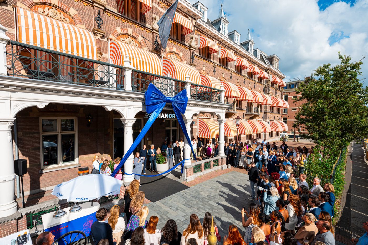 Gasten en buurtbewoners bij de feestelijke heropening van The Manor aan de Linnaeusstraat