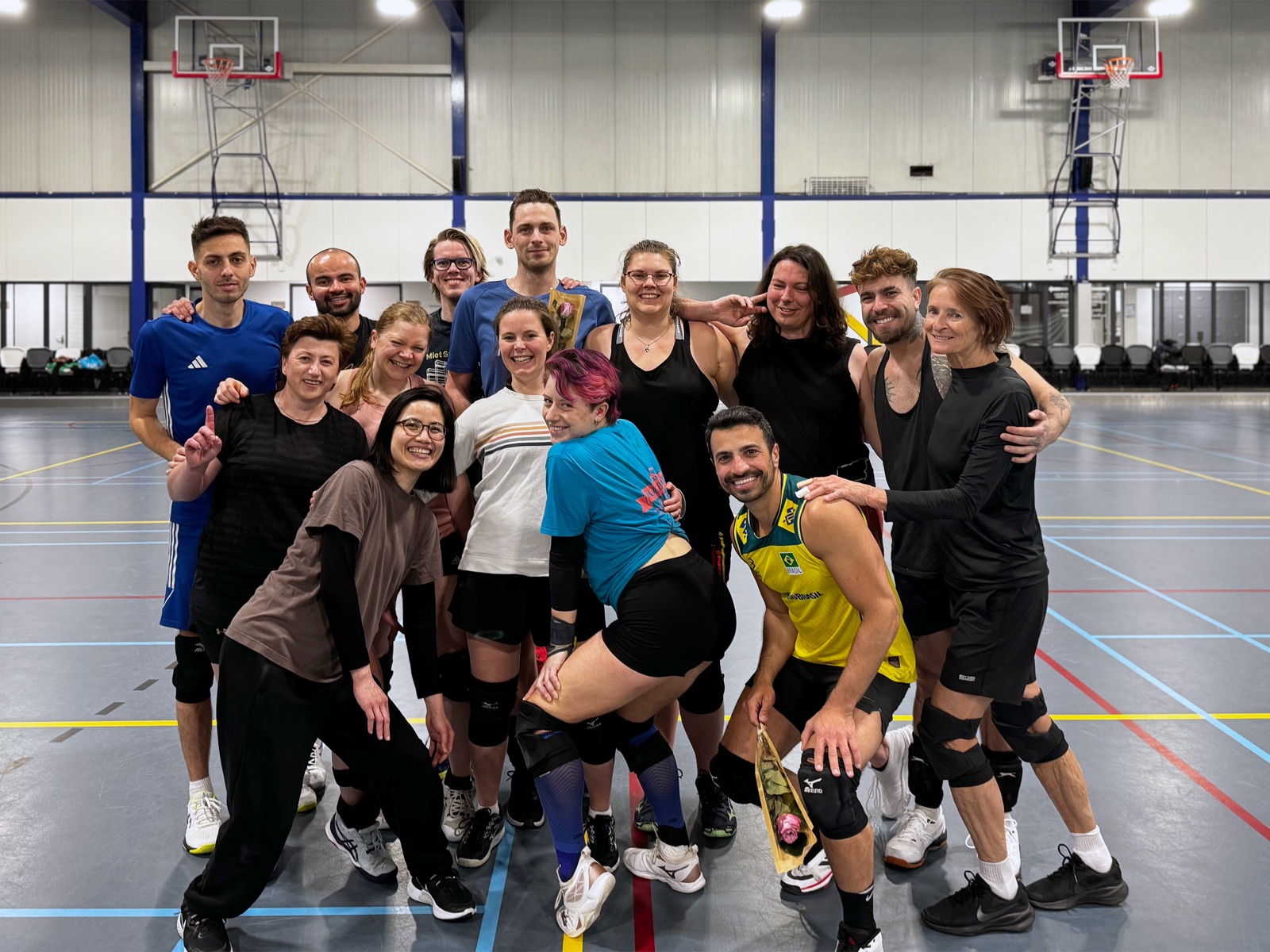 Een gemengde groep Netzo-leden poseert lachend na een training in de sporthal