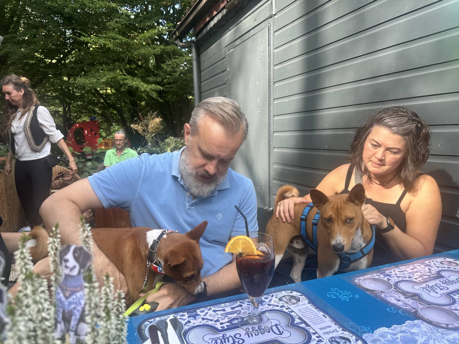 Twee honden aan tafel bij hun baasjes, met voor hen de placemats van het Doggy Style-menu