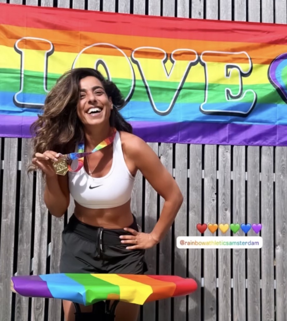 Deelneemster van de Amsterdam Pride Run toont haar medaille voor een regenboogvlag met de tekst LOVE (foto: Rainbow Athletics Amsterdam)