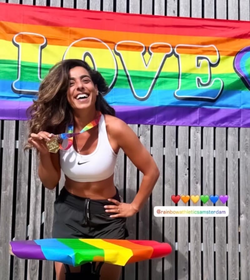 Deelneemster van de Amsterdam Pride Run toont haar medaille voor een regenboogvlag met de tekst LOVE (foto: Rainbow Athletics Amsterdam)