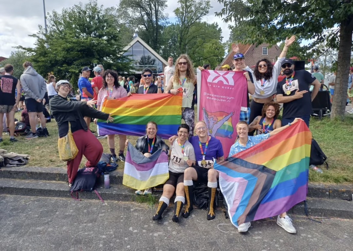 Groep deelnemers van de Amsterdam Pride Run met medailles en regenboogvlaggen (foto: Rainbow Athletics Amsterdam)