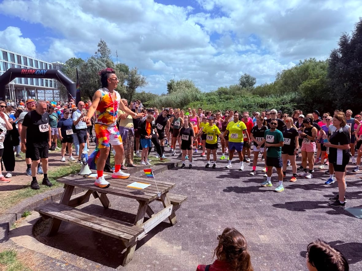 Deelnemers doen een gezamenlijke warming-up voor de start van de Amsterdam Pride Run bij Polder in de Watergraafsmeer