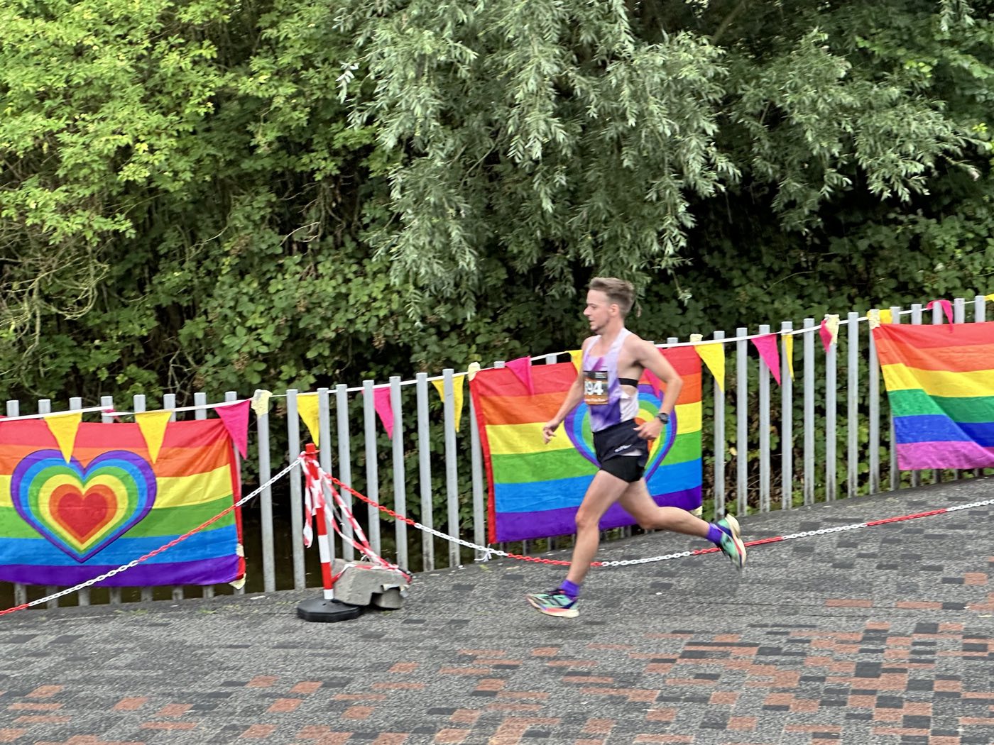 Hardloper tijdens de Amsterdam Pride Run, tussen regenboogvlaggen langs de route