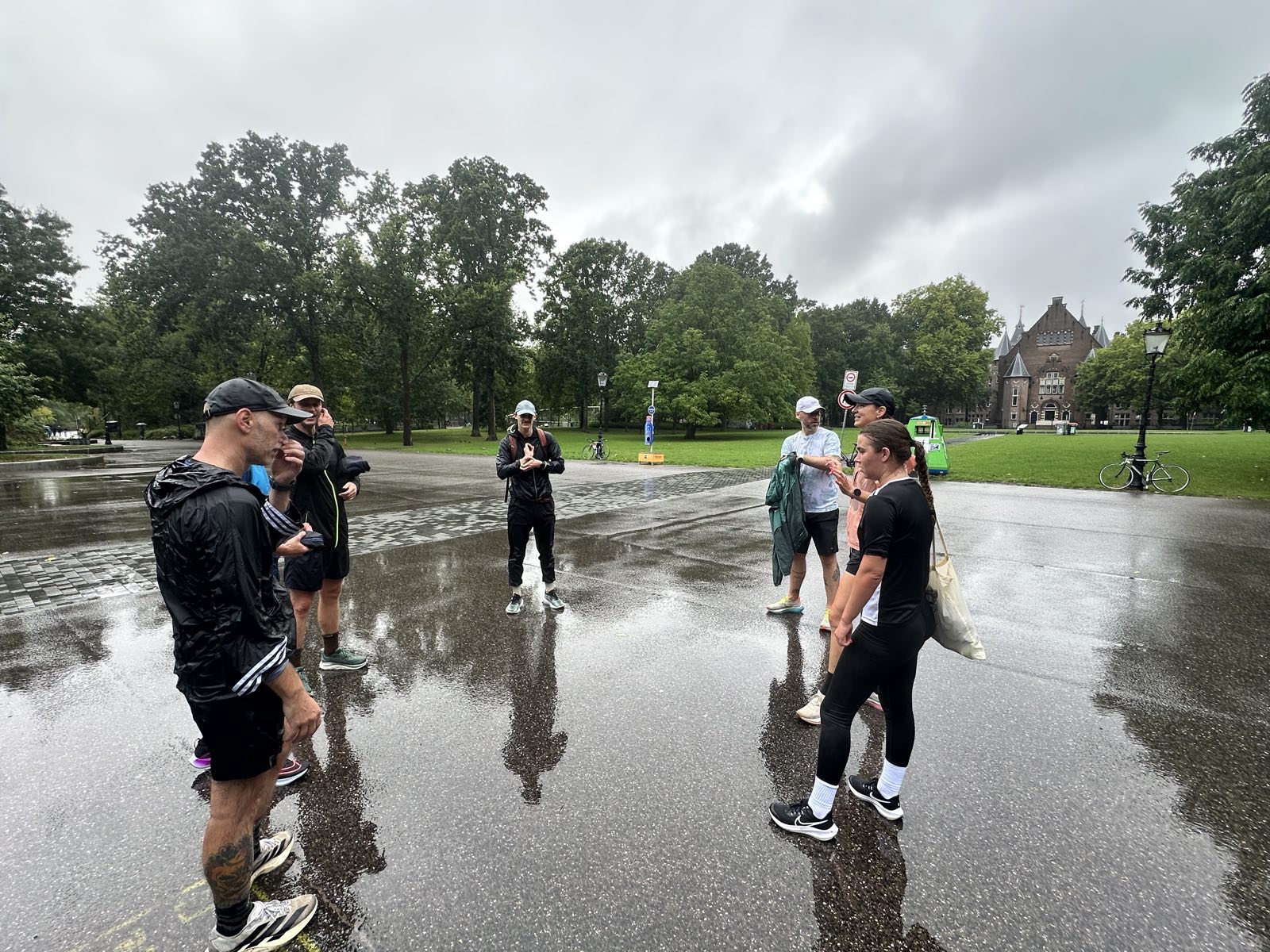 De deelnemers verzamelen zich voor de warming-up op het natte asfalt in het Oosterpark