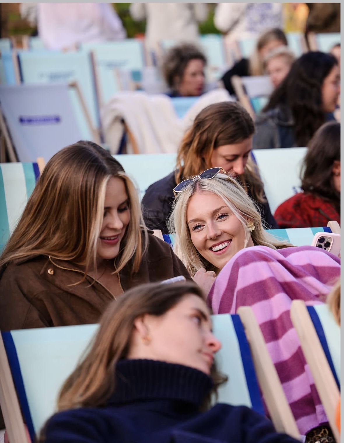Bezoekers onder een deken lachen samen tijdens een filmavond op het dakterras