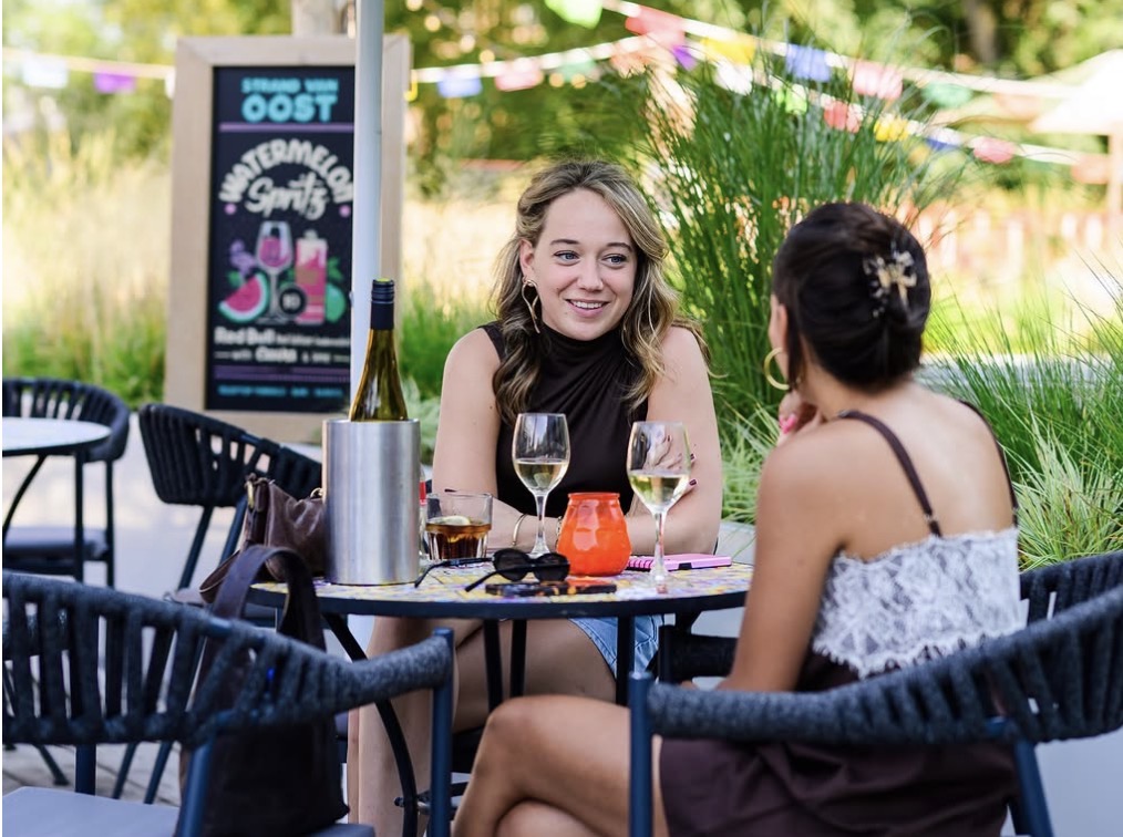Twee bezoekers met drankjes aan een tafeltje op het terras