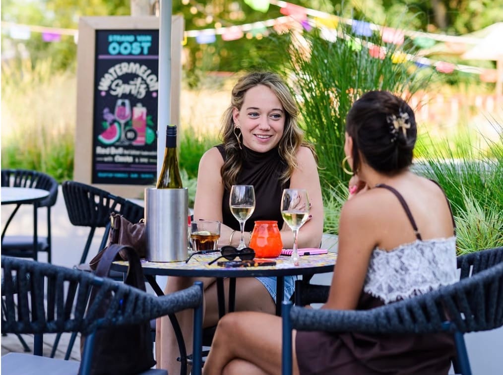 Twee bezoekers met drankjes aan een tafeltje op het terras