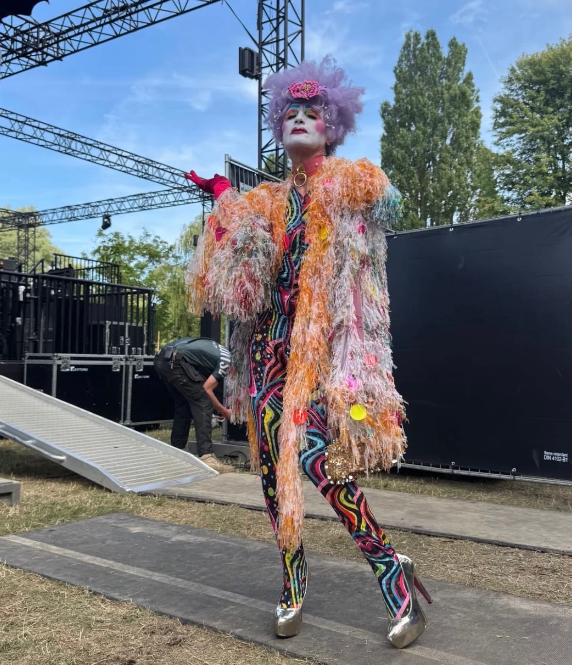 Kleurrijk geklede performer op het podium tijdens Synergy Art Festival in het Flevopark