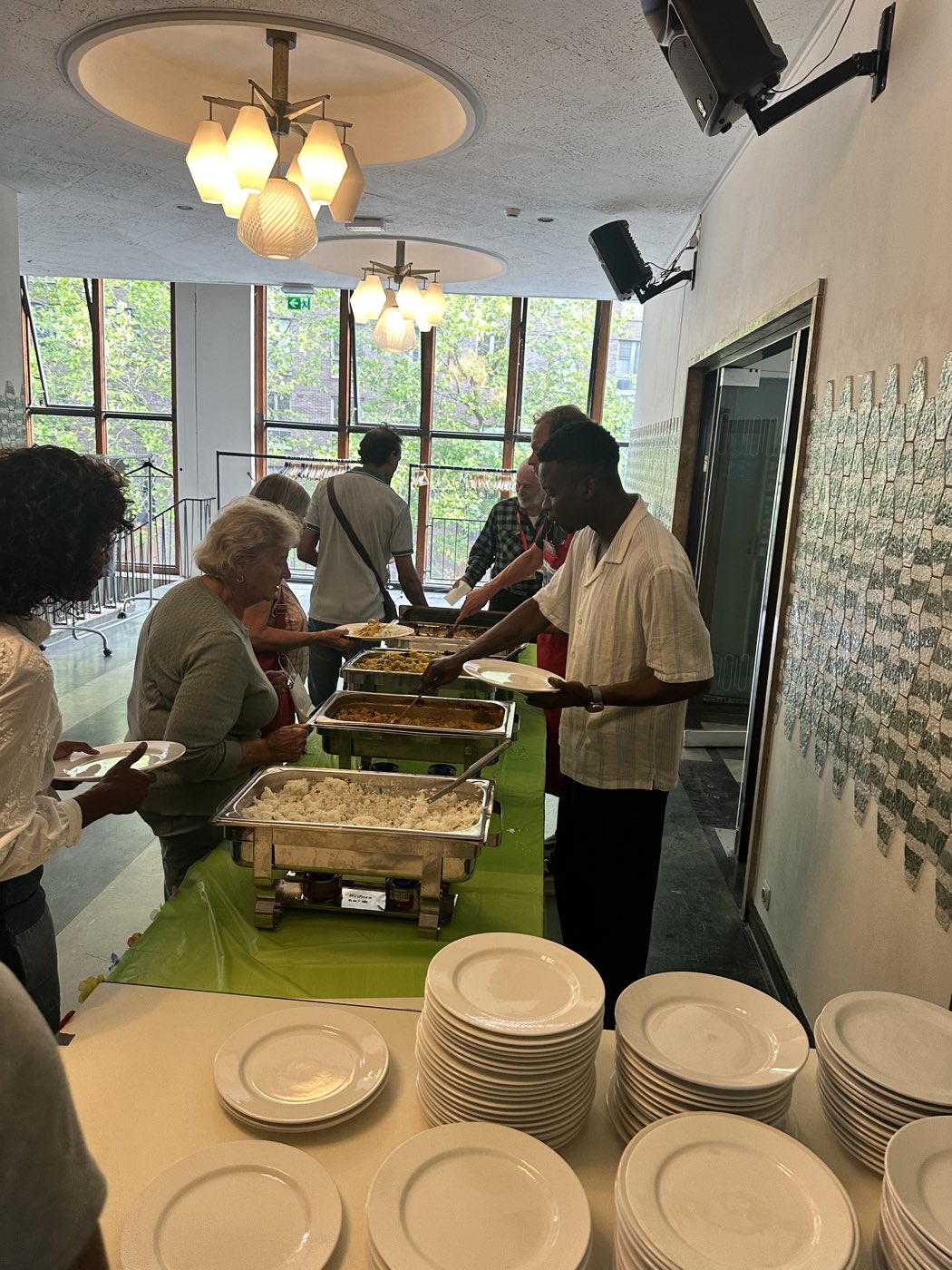 Medewerkers van het stadsdeel scheppen eten op voor de vrijwilligers bij een buffet