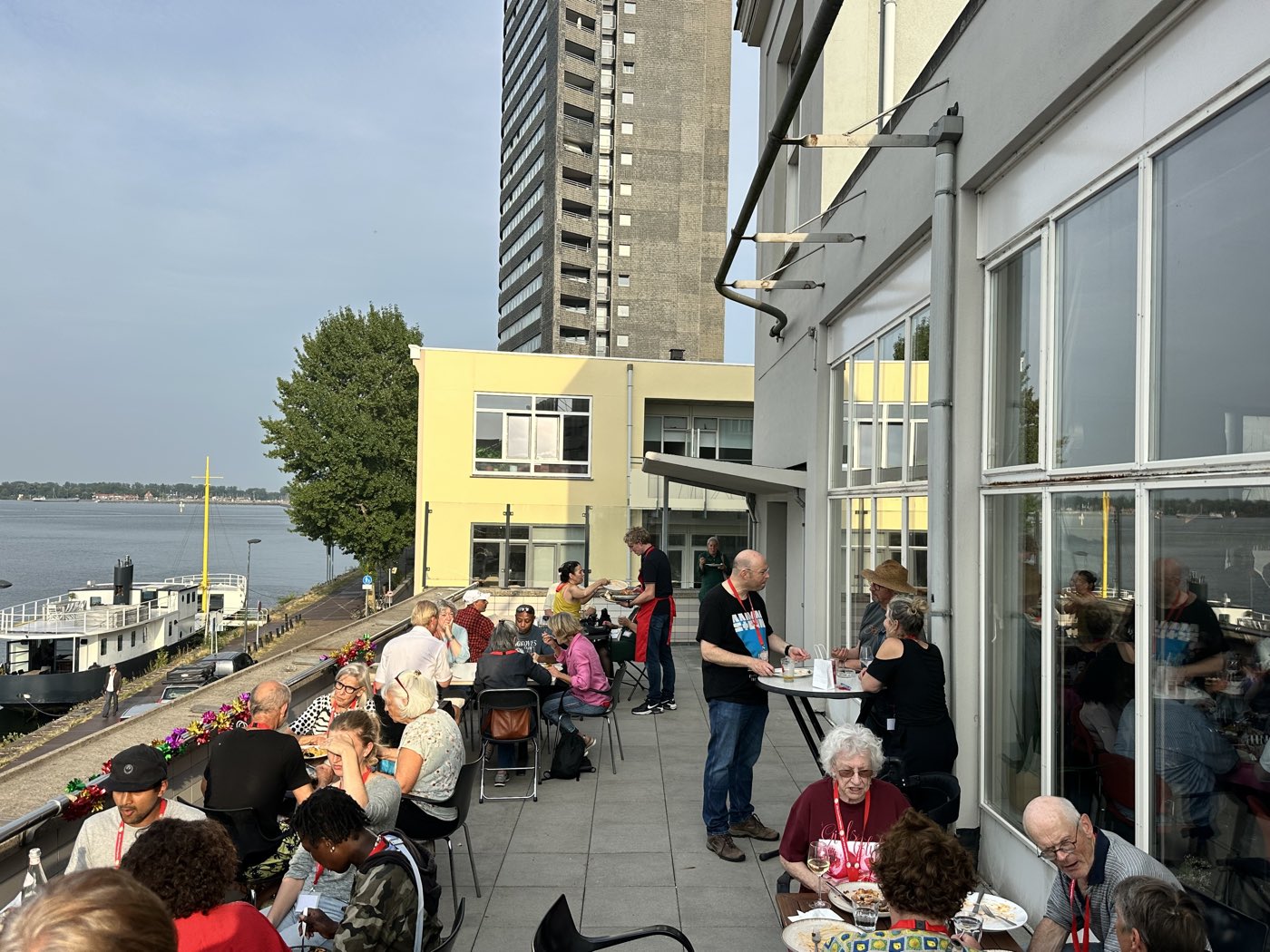 Bezoekers genieten van het uitzicht en elkaars gezelschap op het terras van de Kompaszaal bij zonsondergang