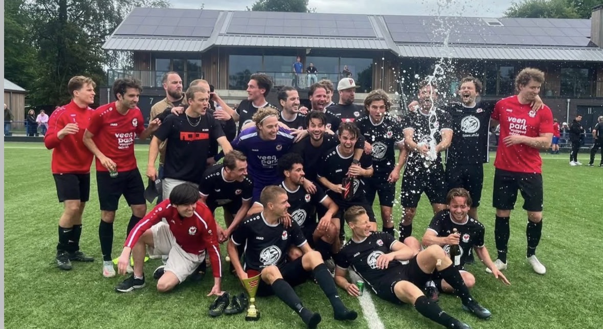 Spelers van WV-HEDW vieren het kampioenschap met champagne en de beker