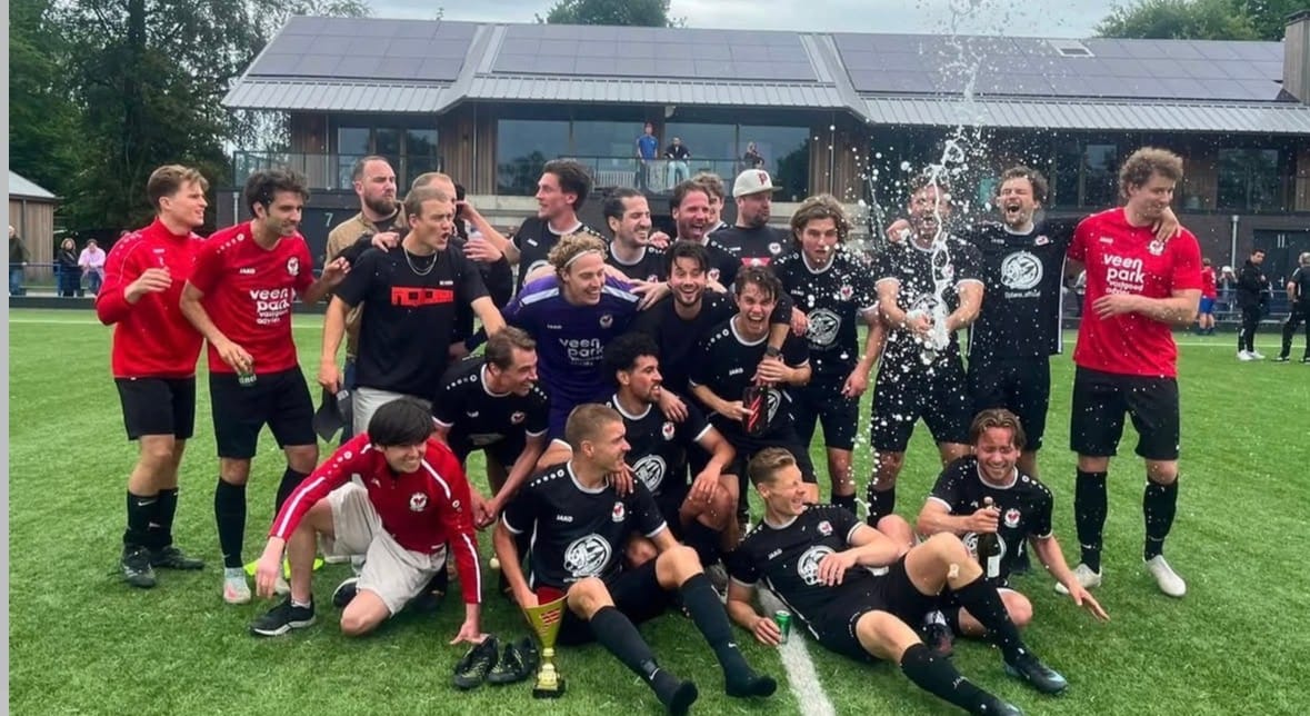 Spelers van WV-HEDW vieren het kampioenschap met champagne en de beker